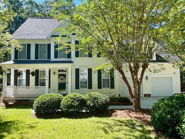 colonial inspired home with a front yard, a garage, and covered porch