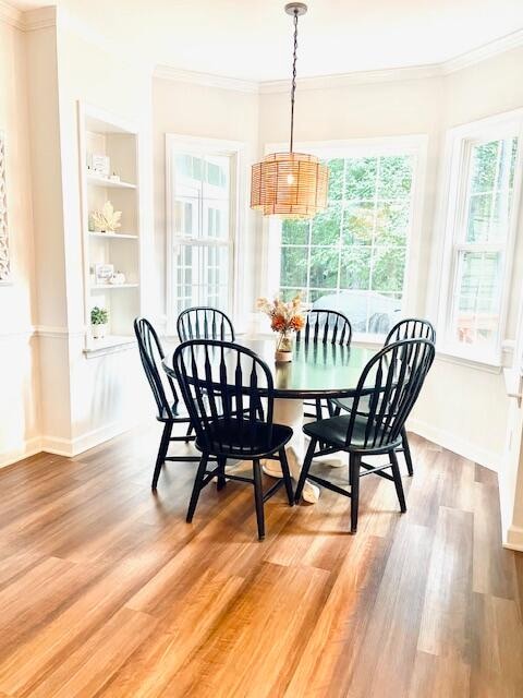 dining space with hardwood / wood-style flooring, crown molding, and built in features