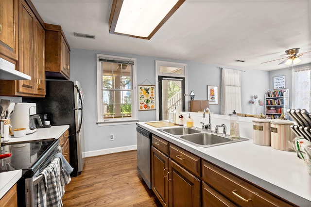 kitchen featuring light hardwood / wood-style floors, stainless steel dishwasher, range with electric cooktop, sink, and ceiling fan