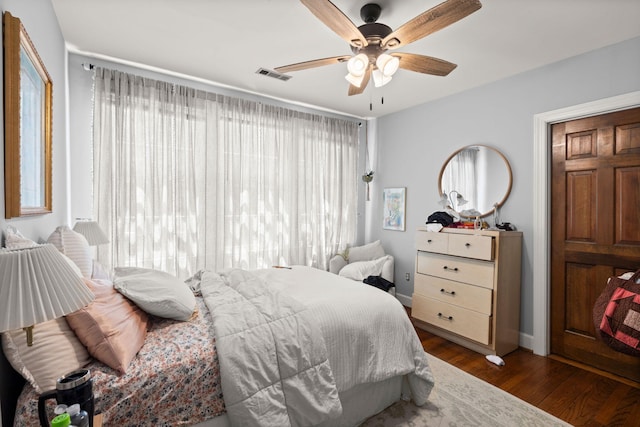 bedroom featuring dark hardwood / wood-style floors, ceiling fan, and multiple windows