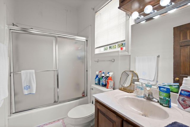 full bathroom with bath / shower combo with glass door, toilet, and vanity