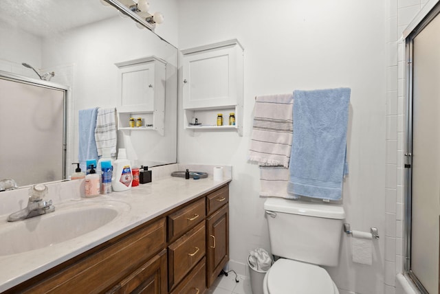 bathroom with tile flooring, an enclosed shower, vanity, and toilet