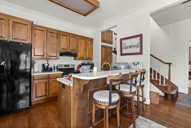 kitchen featuring black fridge with ice dispenser, dark hardwood / wood-style flooring, kitchen peninsula, a breakfast bar area, and electric stove