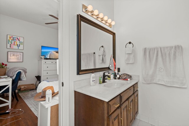 bathroom with ceiling fan, vanity with extensive cabinet space, and hardwood / wood-style floors