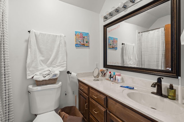 bathroom with toilet, dual sinks, vaulted ceiling, and vanity with extensive cabinet space