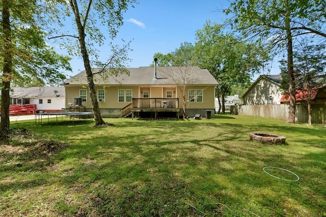 213 Travelers Rest Blvd, Summerville, SC 29485 - rear view of property featuring a trampoline, a wooden deck, an outdoor fire pit, a yard, and fence