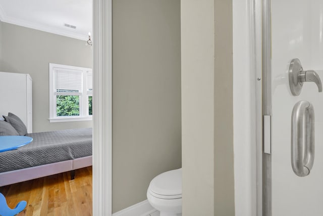 bathroom with crown molding, wood-type flooring, and toilet