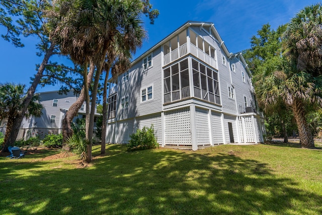 rear view of house featuring a sunroom and a lawn