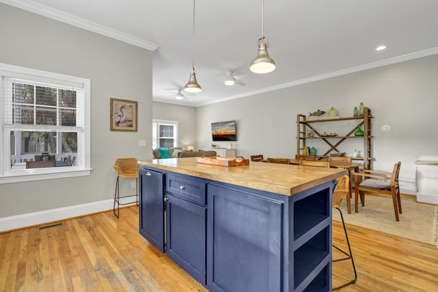 kitchen with wood counters, blue cabinets, a kitchen breakfast bar, hanging light fixtures, and light hardwood / wood-style flooring