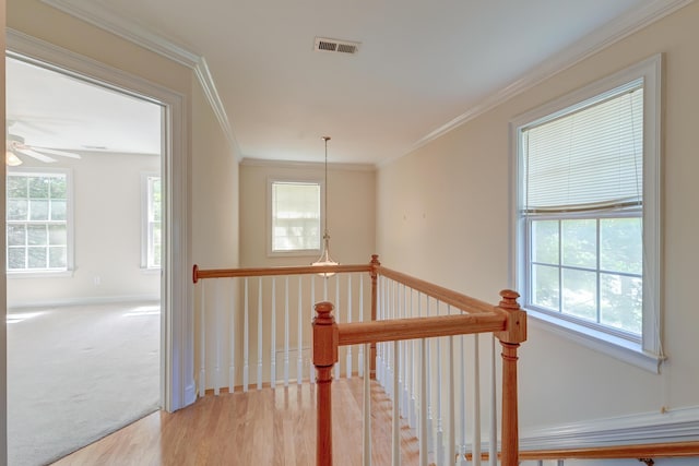 hall with an upstairs landing, wood finished floors, crown molding, and baseboards
