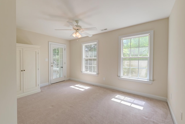 carpeted empty room featuring ceiling fan and baseboards