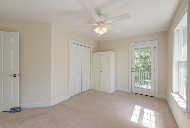 unfurnished bedroom featuring light colored carpet, access to outside, baseboards, and a ceiling fan