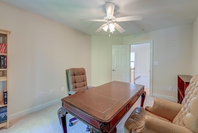 office area with light colored carpet, a ceiling fan, and baseboards