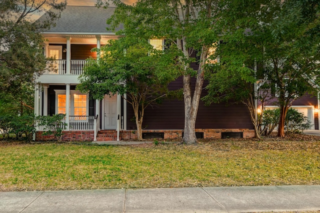 view of front of property featuring a balcony, a porch, a front lawn, crawl space, and a shingled roof