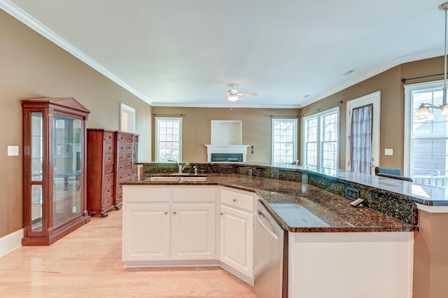 kitchen featuring dishwasher, a sink, a ceiling fan, a fireplace, and white cabinets