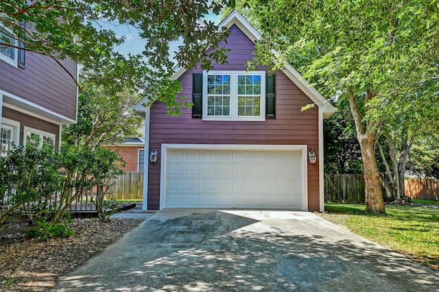 garage with asphalt driveway and fence