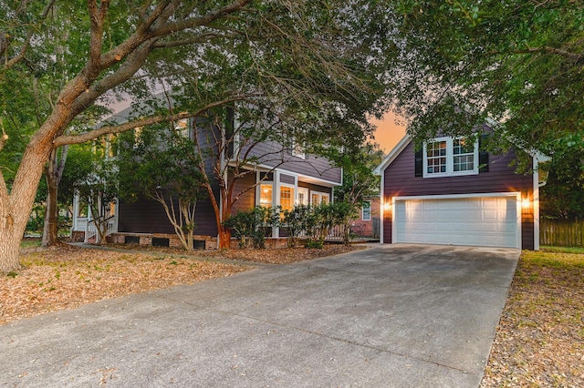 view of property hidden behind natural elements featuring concrete driveway and a garage