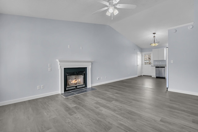 unfurnished living room with a ceiling fan, baseboards, lofted ceiling, a lit fireplace, and dark wood-type flooring