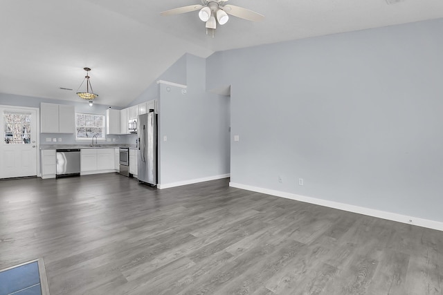 unfurnished living room featuring baseboards, dark wood-style flooring, a sink, ceiling fan, and vaulted ceiling