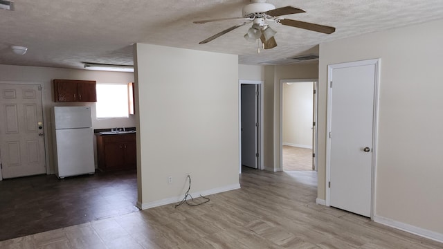 unfurnished room featuring ceiling fan, a textured ceiling, and light hardwood / wood-style flooring