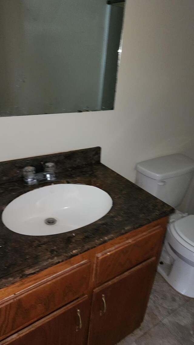 bathroom featuring vanity, tile patterned floors, and toilet