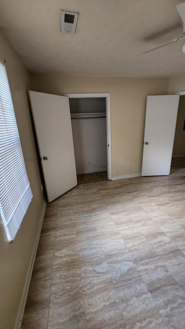 unfurnished bedroom with ceiling fan and a closet