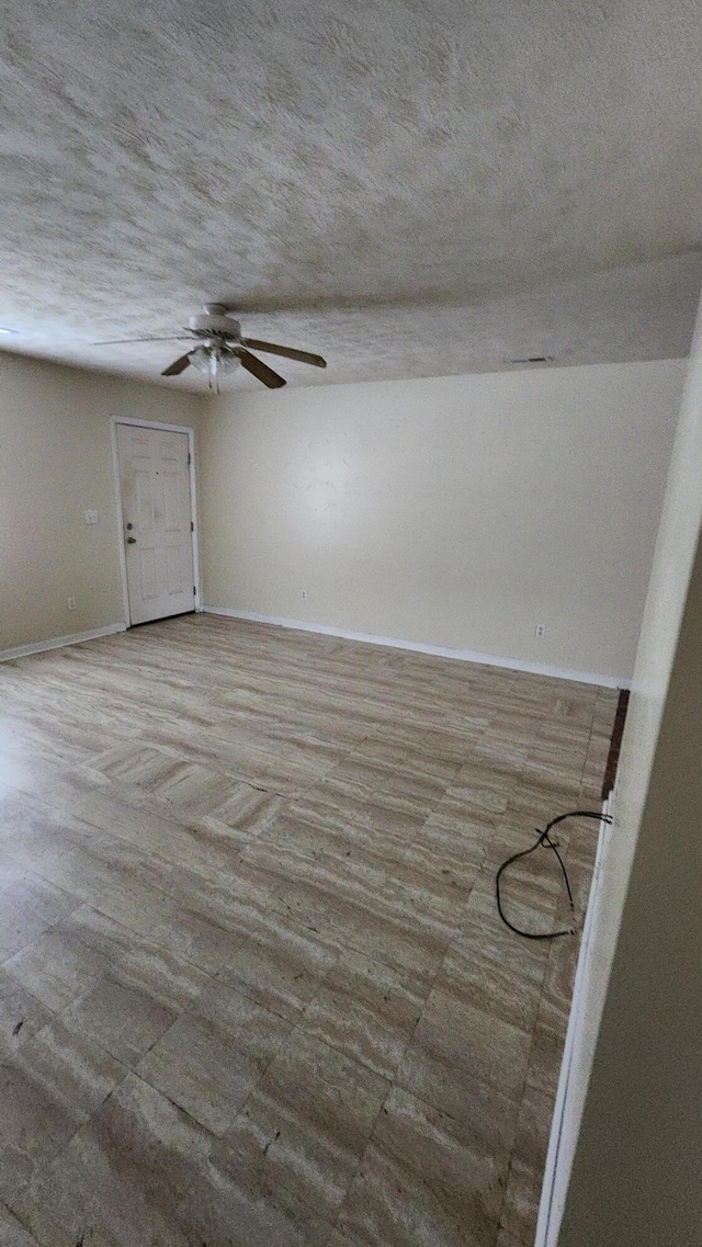 unfurnished room with ceiling fan and a textured ceiling