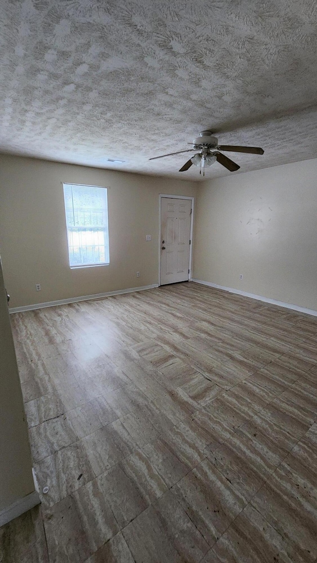 empty room featuring ceiling fan, hardwood / wood-style flooring, and a textured ceiling