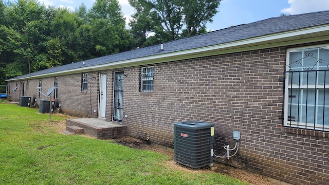 back of house featuring a lawn and central air condition unit