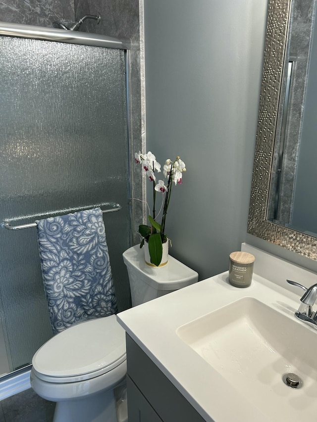 bathroom featuring vanity, toilet, and a shower with door