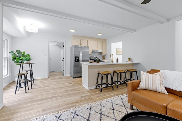 living room featuring ceiling fan, sink, beamed ceiling, and light wood-type flooring