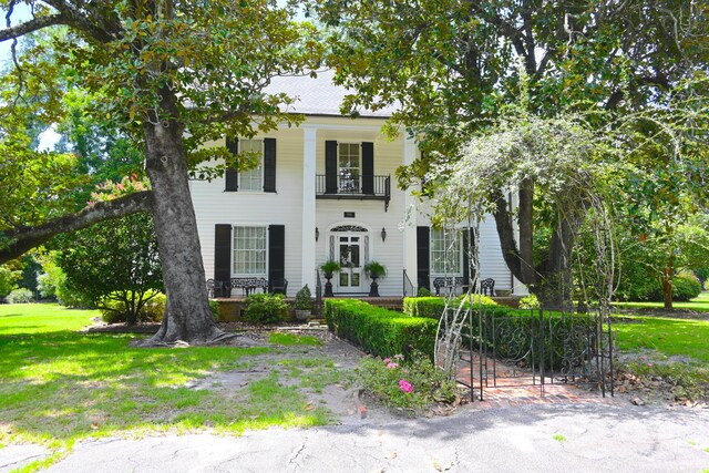 view of front of home featuring a balcony and a front lawn