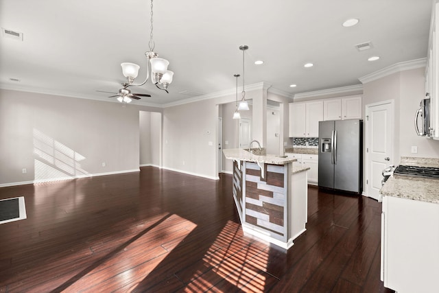 kitchen featuring pendant lighting, white cabinets, appliances with stainless steel finishes, a kitchen island with sink, and light stone counters