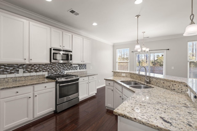 kitchen with decorative light fixtures, sink, stainless steel appliances, and white cabinetry