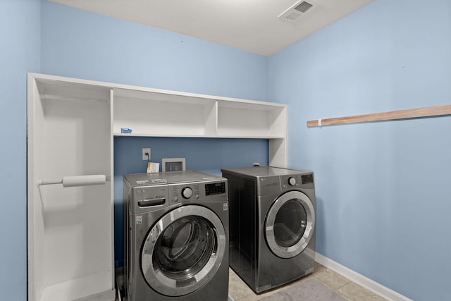 clothes washing area with light tile patterned floors and independent washer and dryer