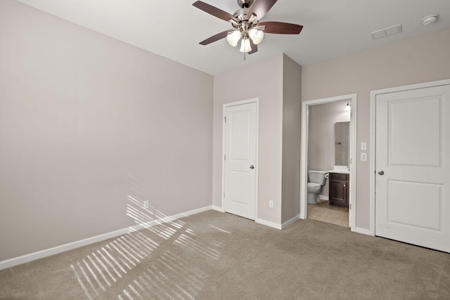 unfurnished bedroom with ceiling fan, a closet, light colored carpet, and ensuite bath