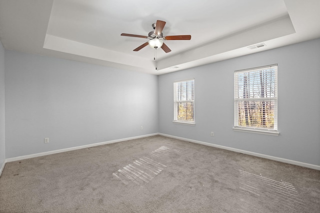 spare room with ceiling fan, carpet flooring, and a tray ceiling