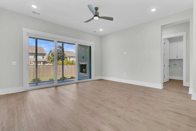 1183 Reserve Ln, Awendaw, SC 29429 - spare room with light wood-type flooring, a ceiling fan, a warm lit fireplace, and recessed lighting