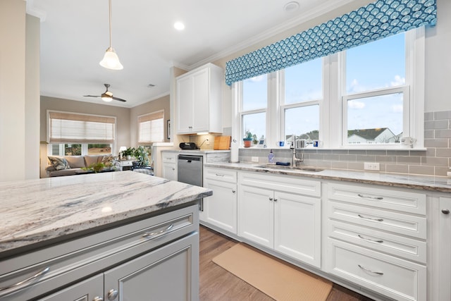 kitchen with sink, white cabinetry, tasteful backsplash, light stone counters, and decorative light fixtures