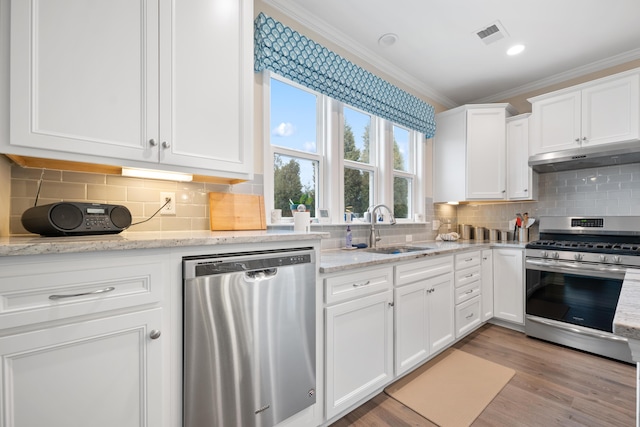 kitchen featuring sink, white cabinets, ornamental molding, light stone counters, and stainless steel appliances