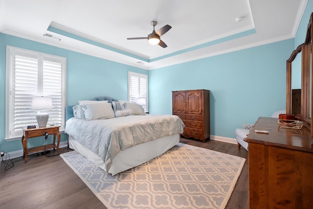 bedroom featuring crown molding, dark wood-type flooring, a raised ceiling, and ceiling fan