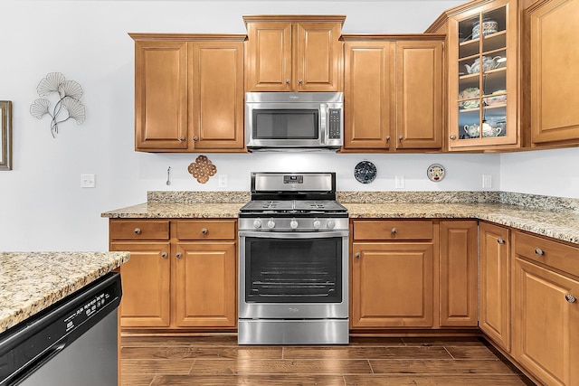 kitchen with appliances with stainless steel finishes, dark hardwood / wood-style floors, and light stone countertops