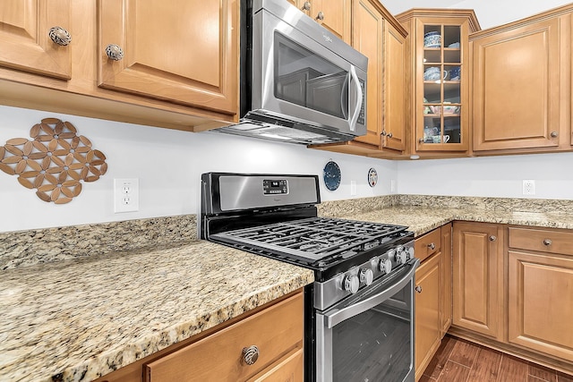 kitchen featuring appliances with stainless steel finishes, light stone counters, and dark hardwood / wood-style floors