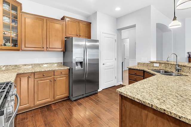 kitchen featuring light stone countertops, stainless steel appliances, hanging light fixtures, and sink