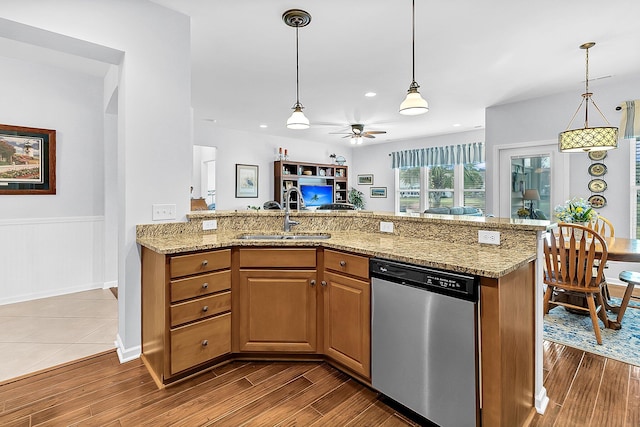 kitchen with sink, hanging light fixtures, ceiling fan, light stone counters, and stainless steel dishwasher