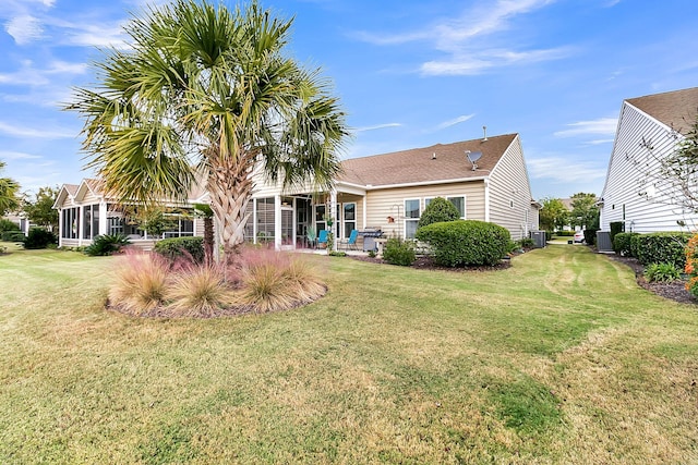 back of house with a sunroom, a lawn, and central air condition unit