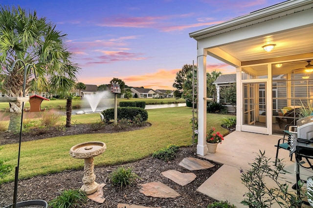 yard at dusk with a sunroom and a water view