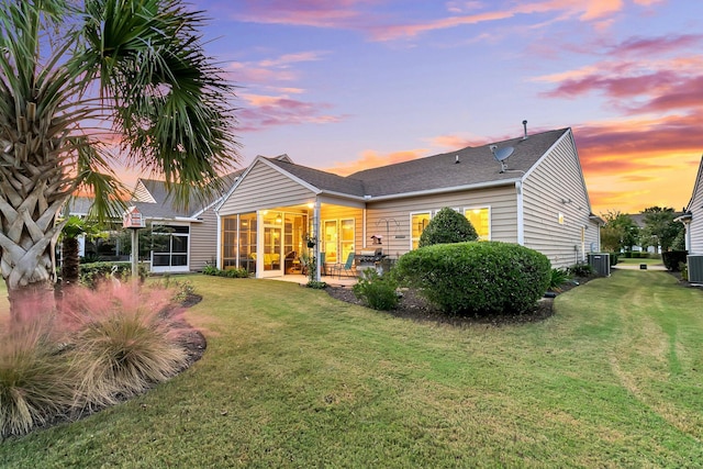 back house at dusk with cooling unit, a patio, a yard, and a sunroom