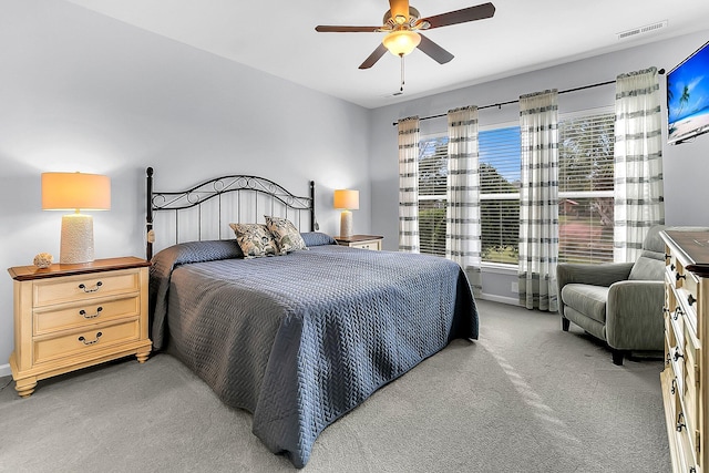 bedroom featuring ceiling fan, multiple windows, and light carpet