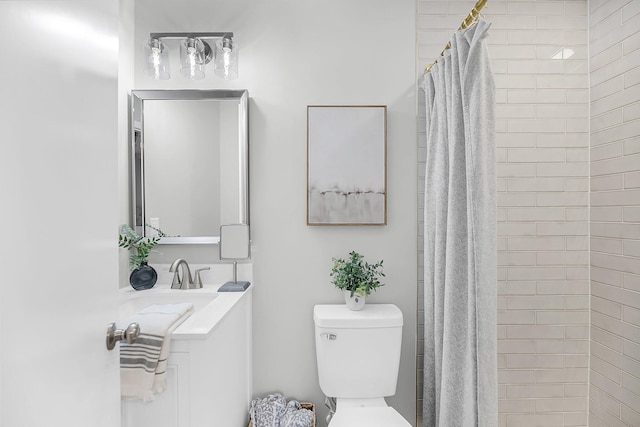 full bathroom with vanity, toilet, and tiled shower